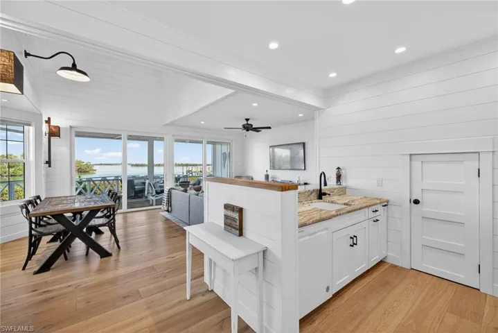 Kitchen with a peninsula, wood walls, white cabinetry, light stone countertops, and light wood-style floors