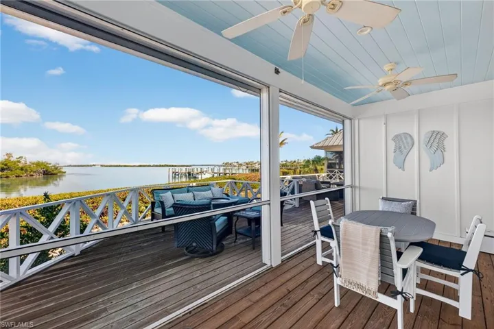 View from the screened in poch on the 1st floor across exterior Wooden deck with a water view, outdoor dining area, an outdoor living space, and a ceiling fan