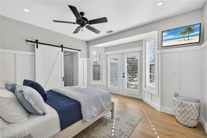 1st floor Bedroom featuring a barn door, light wood-style flooring, direct access to back deck seating area, ceiling fan