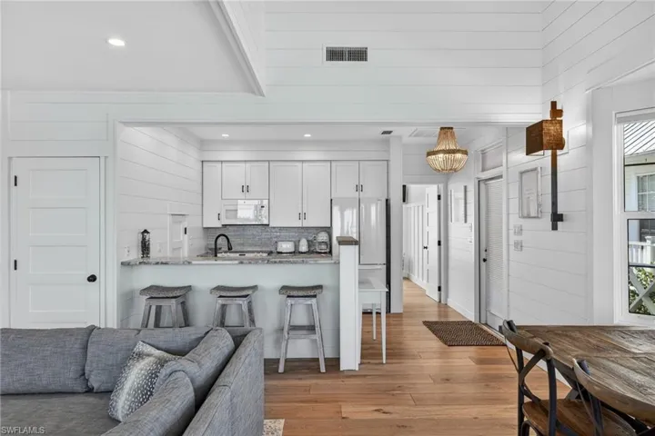 Kitchen featuring white cabinets, white appliances, wood walls, light wood-type flooring, and open floor plan