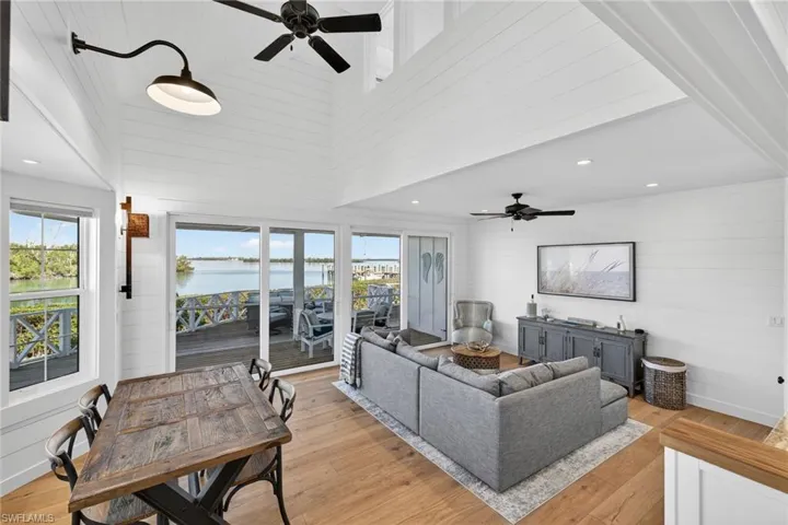 Living and dining areas with view across porch and deck to open water