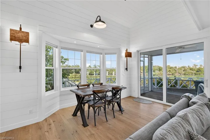Dining room with light wood finished floors, wood walls, a water view, healthy amount of natural light, and lofted ceiling