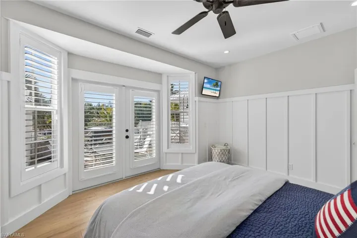 Bedroom featuring access to exterior, a decorative wall, a ceiling fan, wainscoting, and recessed lighting
