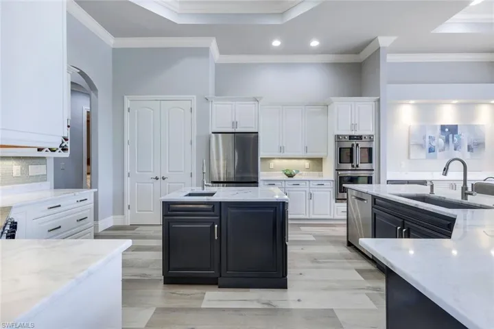 Kitchen with appliances with stainless steel finishes, white cabinetry, decorative backsplash, and sink