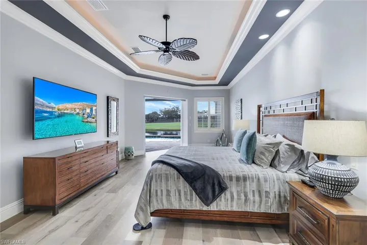 Bedroom featuring access to outside, ceiling fan, light hardwood / wood-style floors, a raised ceiling, and ornamental molding