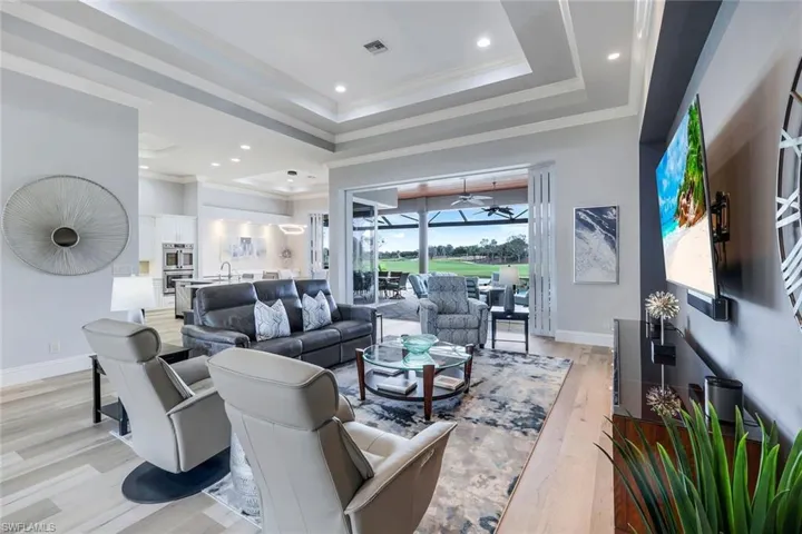 Living room with ornamental molding, sink, light wood-type flooring, and a tray ceiling