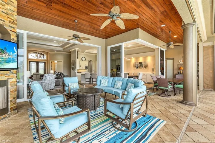 Living room with decorative columns, light tile patterned floors, and ceiling fan