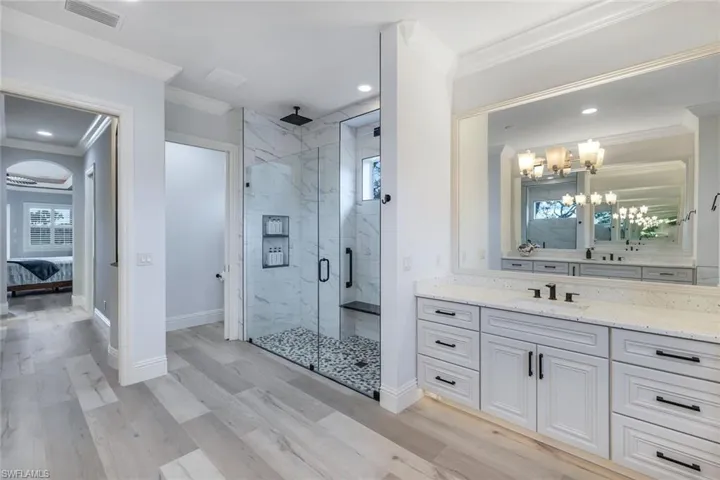 Bathroom featuring a notable chandelier, crown molding, an enclosed shower, vanity, and wood-type flooring