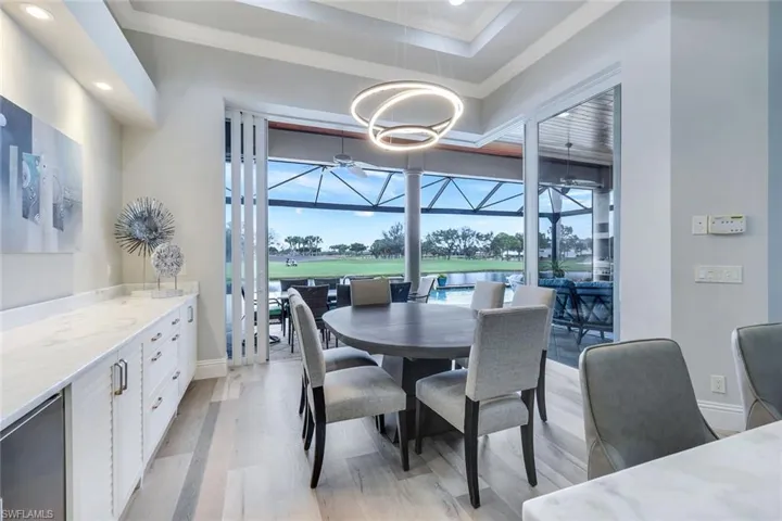 Dining space with a raised ceiling, light hardwood / wood-style flooring, and a chandelier