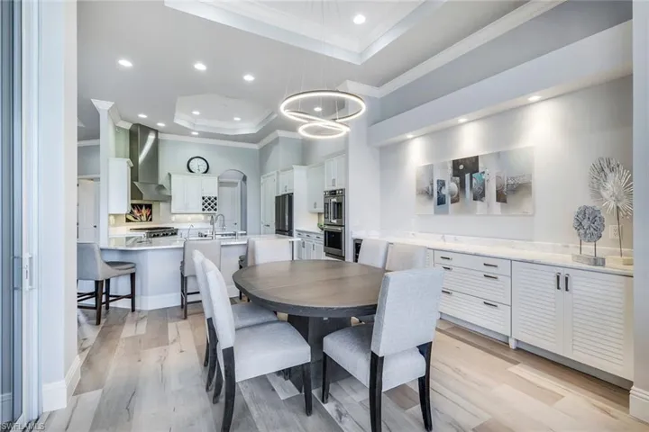 Dining space with sink, light hardwood / wood-style flooring, crown molding, and a tray ceiling