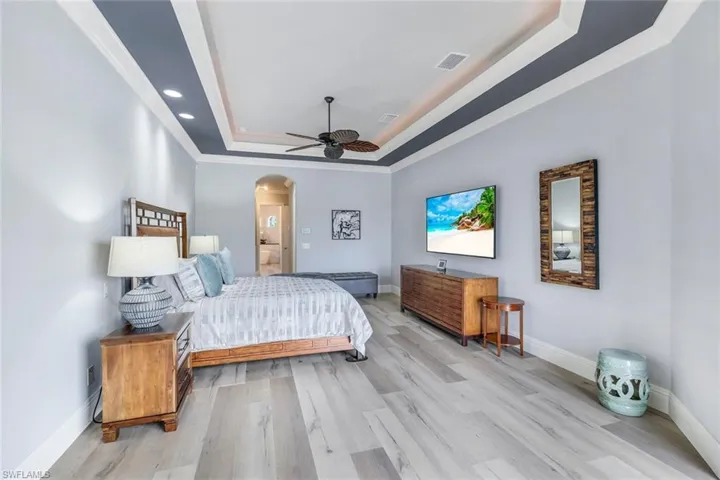 Bedroom featuring ceiling fan, light hardwood / wood-style flooring, a raised ceiling, and ornamental molding