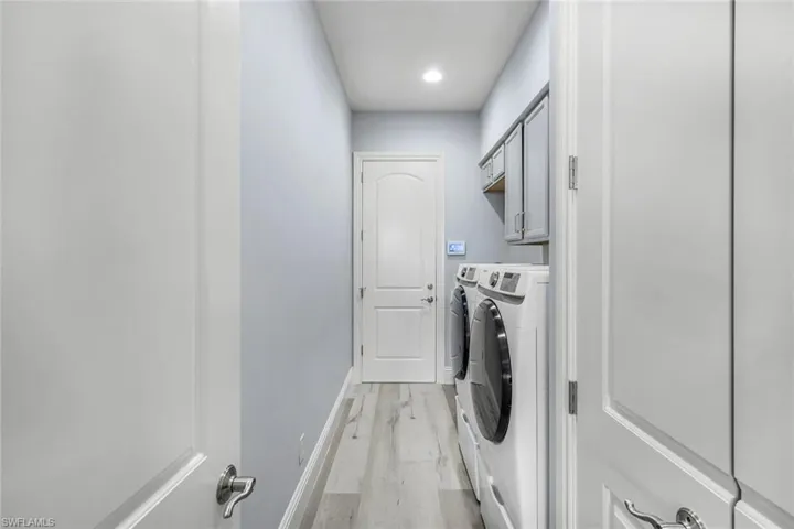 Washroom featuring cabinets, independent washer and dryer, and light hardwood / wood-style floors