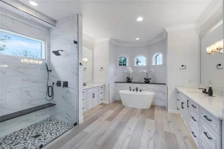 Bathroom with tile walls, shower with separate bathtub, crown molding, and vanity