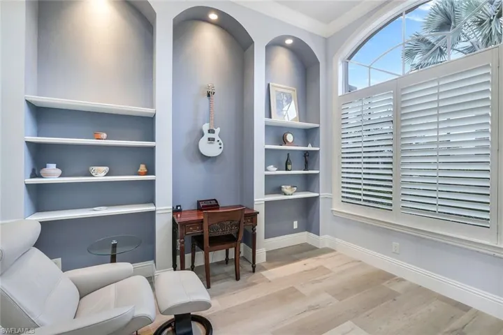 Office area featuring built in shelves, light hardwood / wood-style flooring, and ornamental molding