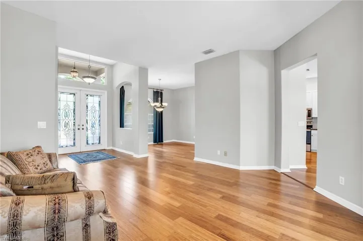 Unfurnished living room featuring a chandelier, french doors, and light wood-type flooring