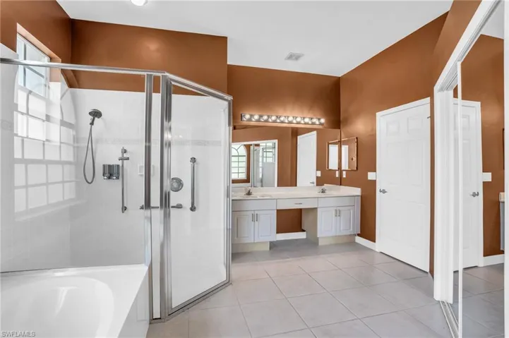 Bathroom featuring tile floors, independent shower and bath, and dual bowl vanity
