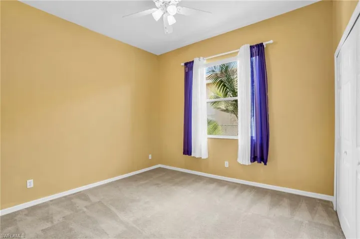 Carpeted spare room with plenty of natural light and ceiling fan