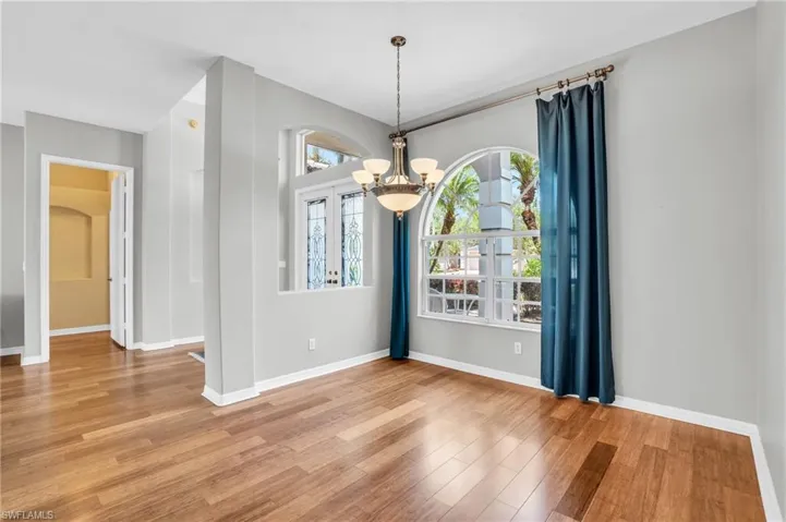 Spare room with a healthy amount of sunlight, a chandelier, and light hardwood / wood-style flooring