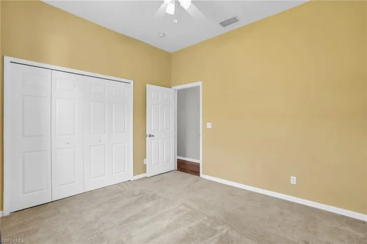 Unfurnished bedroom featuring carpet flooring, a closet, and ceiling fan