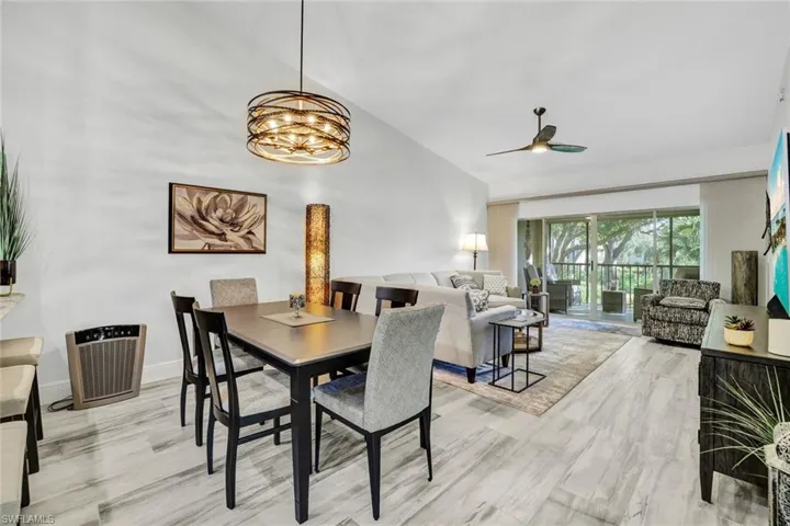 Dining space with tile that looks like wood flooring throughout and ceiling fan with notable chandelier