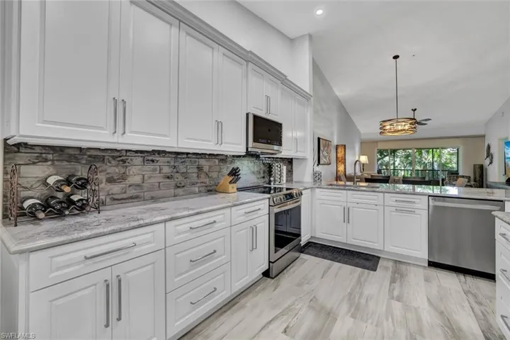 Kitchen featuring appliances with stainless steel finishes, sink, kitchen peninsula, decorative light fixtures, and decorative backsplash