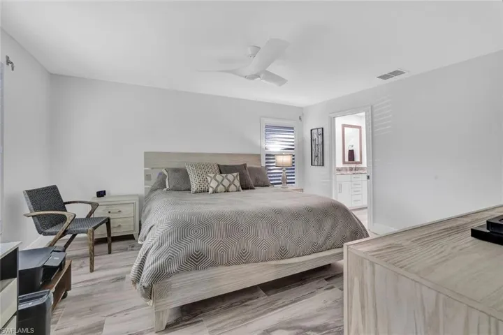 Bedroom featuring Tile that looks like wood plank floors, ensuite bathroom, and ceiling fan