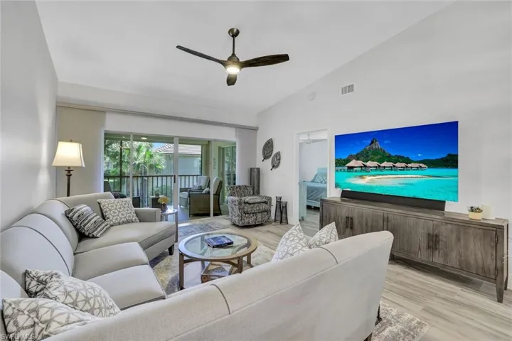Living room featuring tile that looks like wood planks floors, high vaulted ceiling, and ceiling fan
