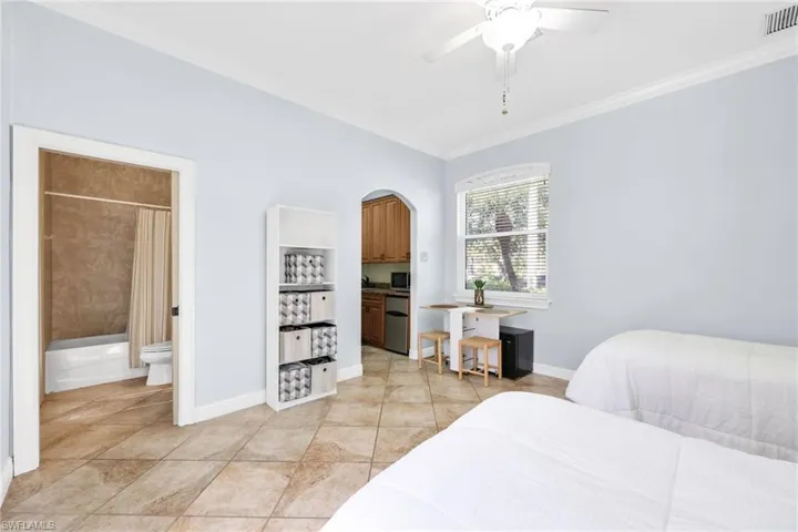 Bedroom featuring ornamental molding, ceiling fan, stainless steel refrigerator, and light tile patterned floors