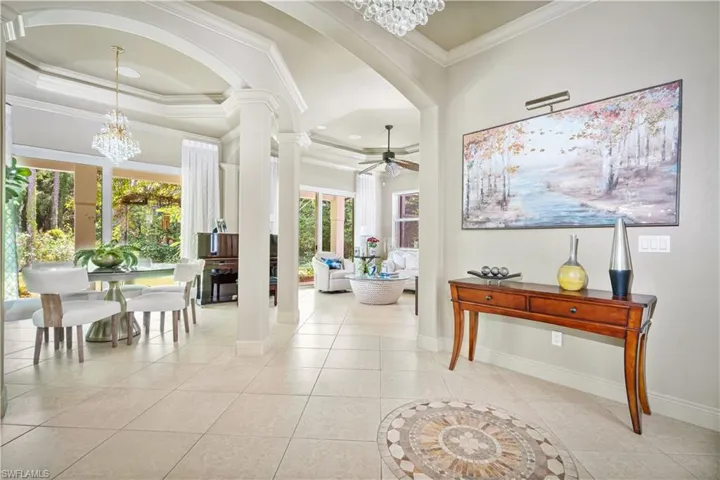 Hallway with a chandelier, arched walkways, crown molding, light tile patterned floors, and plenty of natural light