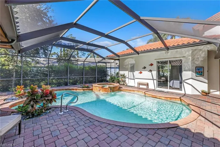 View of pool featuring glass enclosure, a patio area, a pool with connected hot tub, and a sunroom