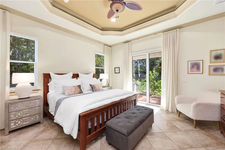 Bedroom featuring a tray ceiling, crown molding, access to exterior, ceiling fan, and light tile patterned flooring