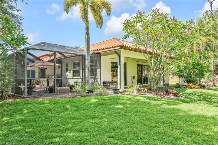 Back of house featuring a tiled roof, a yard, stucco siding, and glass enclosure