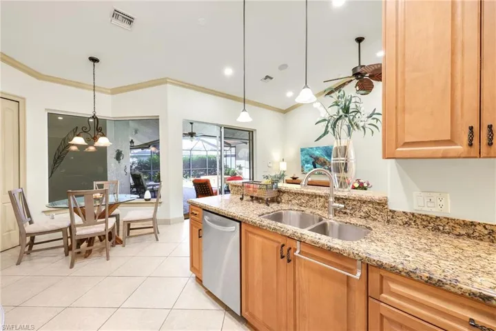 Kitchen featuring decorative light fixtures, light stone countertops, crown molding, light tile patterned floors, and recessed lighting