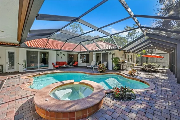 View of pool with glass enclosure, a patio, a sunroom, a pool with connected hot tub, and outdoor lounge area