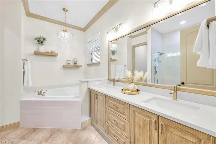 Full bath with a stall shower, crown molding, double vanity, a garden tub, and light tile patterned floors
