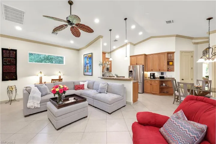 Living room with crown molding, a chandelier, light tile patterned flooring, recessed lighting, and high vaulted ceiling