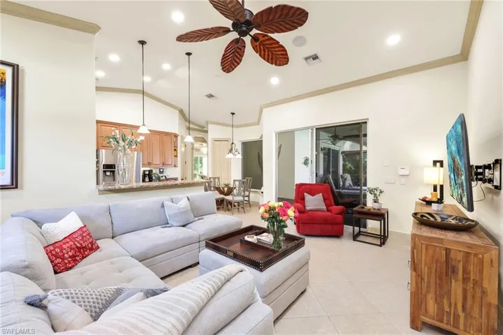 Living room with ornamental molding, light tile patterned floors, a ceiling fan, recessed lighting, and high vaulted ceiling
