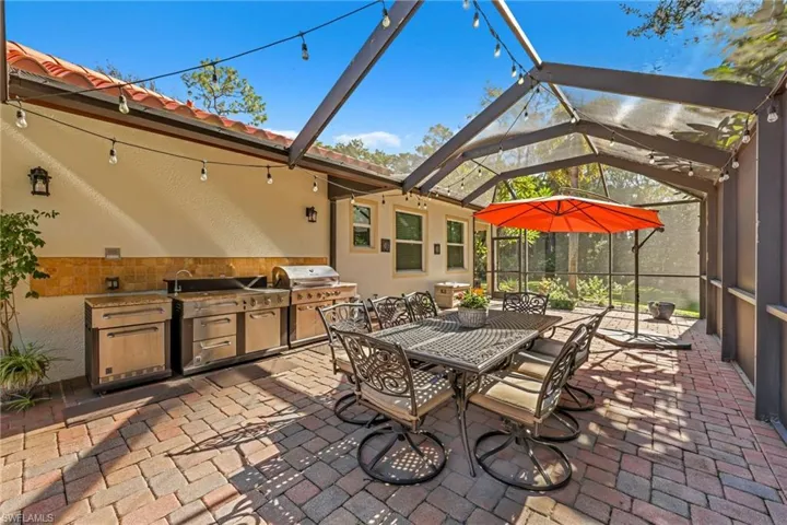 View of patio with a sunroom, glass enclosure, an outdoor kitchen, and outdoor dining area