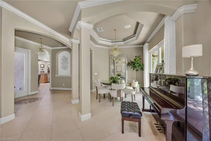 Dining room with a chandelier, light tile patterned flooring, a raised ceiling, and ornamental molding