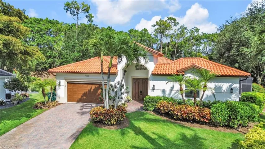 Mediterranean / spanish house featuring a tiled roof, decorative driveway, an attached garage, a front lawn, and stucco siding