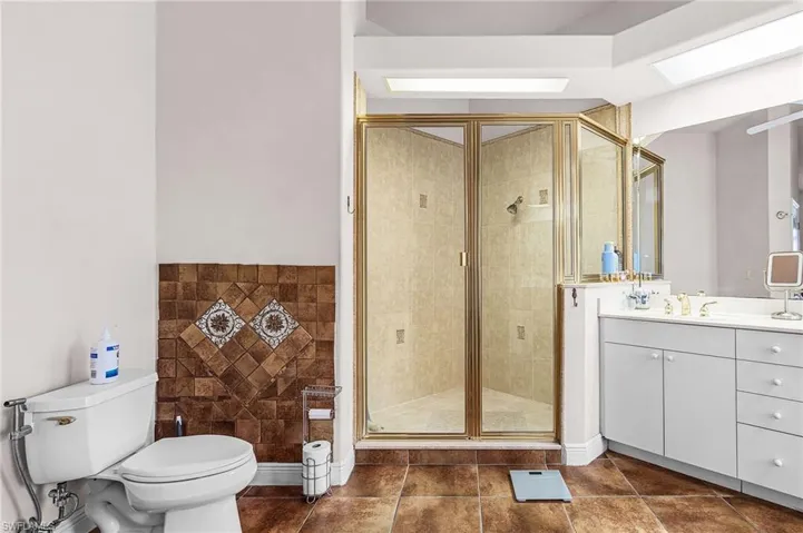 Bathroom with vanity, a stall shower, and dark tile patterned flooring