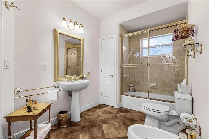 Bathroom with a bidet and bath / shower combo with glass door