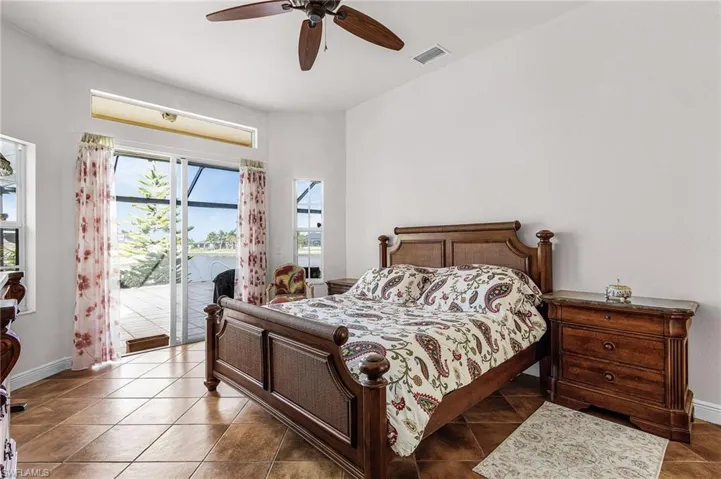Bedroom featuring access to exterior, a ceiling fan, a water view, and tile patterned flooring