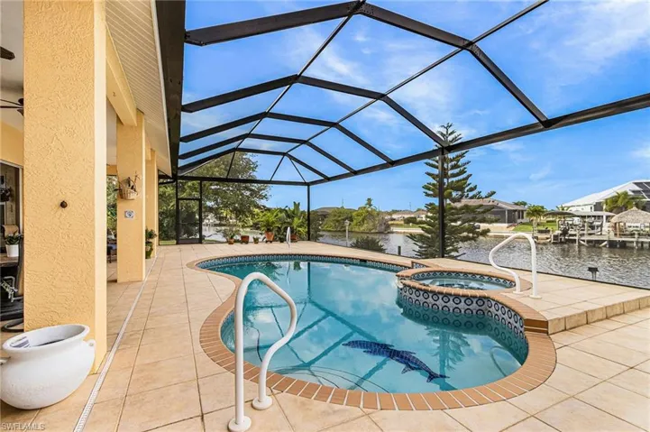 View of swimming pool featuring a sunroom, a water view, a patio area, a pool with connected hot tub, and glass enclosure