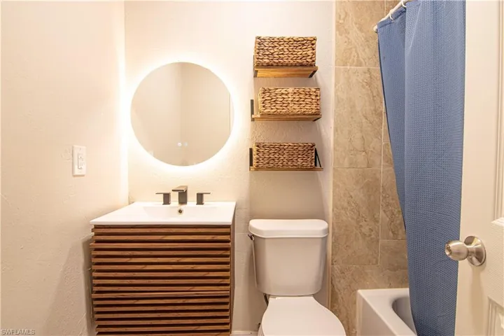 Full bathroom featuring vanity, a textured wall, and shower / bathtub combination with curtain