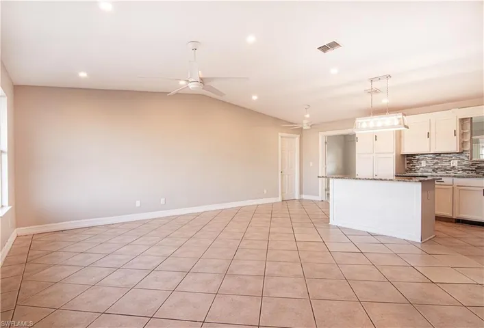 Kitchen featuring a center island, pendant lighting, open floor plan, light tile patterned flooring, and ceiling fan