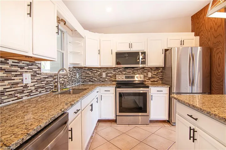 Kitchen featuring lofted ceiling, appliances with stainless steel finishes, and white cabinetry