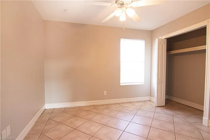 Unfurnished bedroom with ceiling fan, light tile patterned floors, and a closet