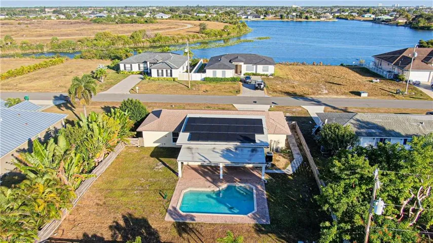 Aerial view of residential area featuring a nearby body of water and a pool area