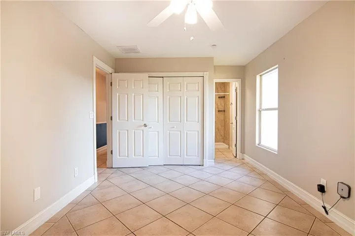 Unfurnished bedroom with light tile patterned flooring, ceiling fan, and a closet